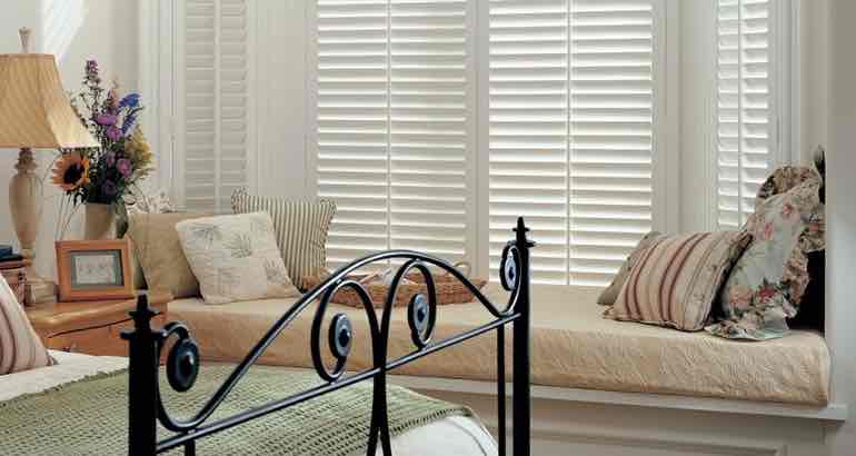 Plantation shutters in a chic bedroom bay window.